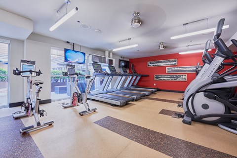 two treadmills and other exercise equipment in a gym with a tv